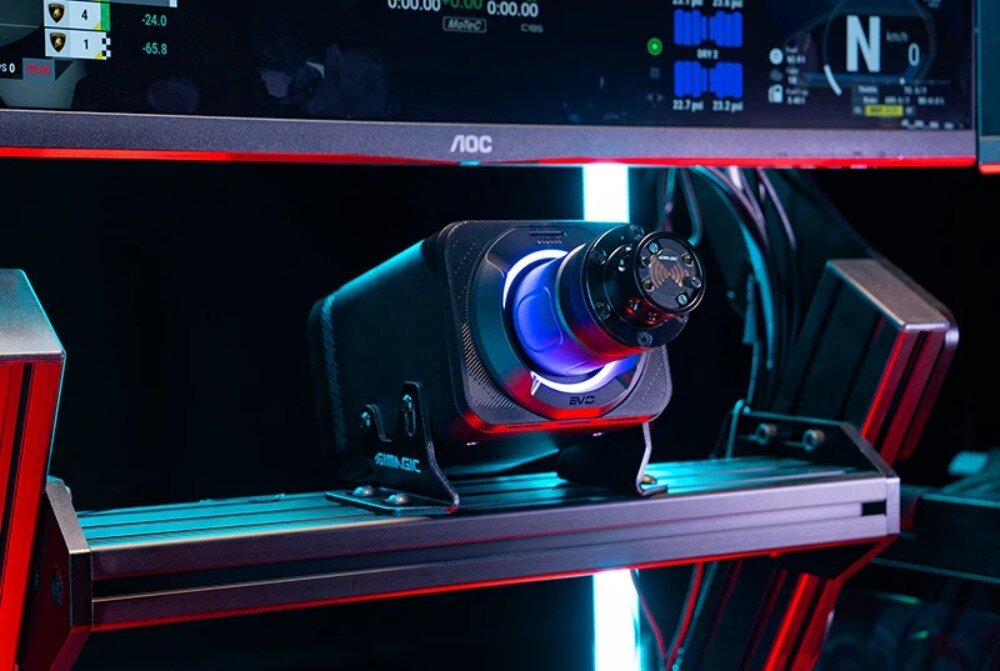 Baza kierownicy SIMAGIC Alpha Evo Baza kierownicy zamontowana na metalowym stelażu kokpitu wyścigowego, umieszczona bezpośrednio pod panoramicznym monitorem