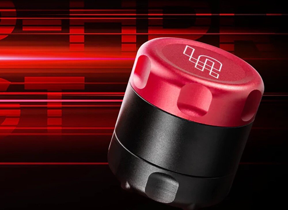 Liniowy reaktor haptyczny SIMAGIC P-HPR GT Metalowy silniczek haptyczny o cylindrycznym kształcie z wygrawerowanym logo na górnej pokrywie, przedstawiony na dynamicznym tle