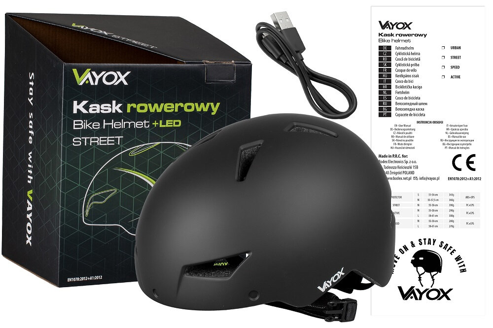 Czarny kask rowerowy z logo VAYOX, obok znajduje się pudełko z napisem \'Kask rowerowy Bike Helmet +LED STREET\'. W zestawie widoczny jest kabel USB oraz instrukcja z logo VAYOX.