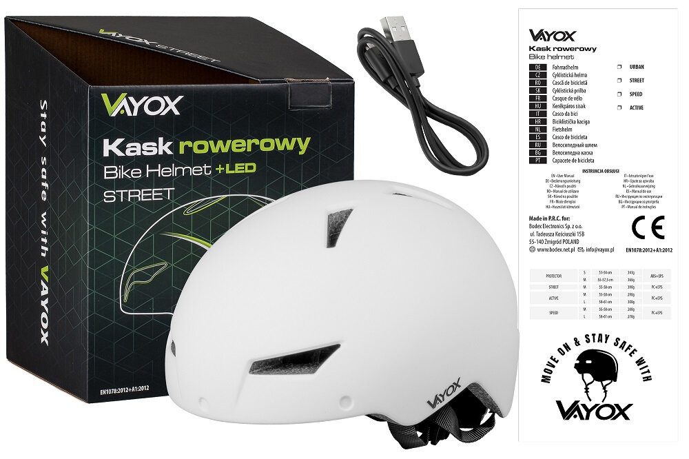 Na obrazie znajduje się biały kask rowerowy z logo VAYOX oraz czarny kabel USB. Obok kasku widoczny jest czarny karton z napisem \'Kask rowerowy Bike Helmet +LED STREET\'.