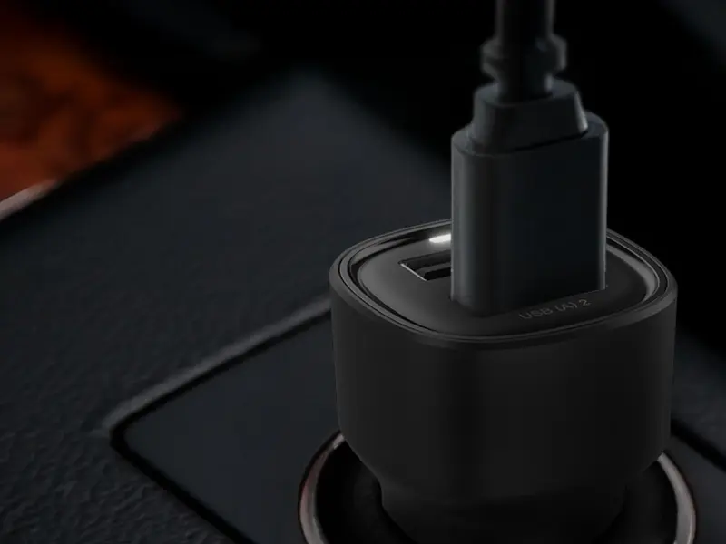 Czarna ładowarka samochodowa z dwoma portami USB-A, z jednym podłączonym kablem. Na obudowie widoczny jest napis \'USB (A) 2\'.