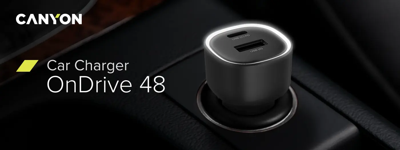 Na zdjęciu widoczna jest czarna ładowarka samochodowa z dwoma portami: USB-C PD i USB-A, umieszczona w gnieździe samochodowym. Obok znajduje się tekst: \'CANYON Car Charger OnDrive 48\'.