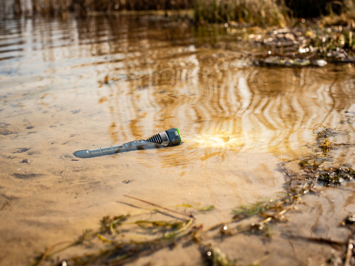 Latarka taktyczna VAYOX VA0364, Wytrzymała i wodoodporna, Latarka włączona i zanurzona do połowy na brzegu basenu wodnego
