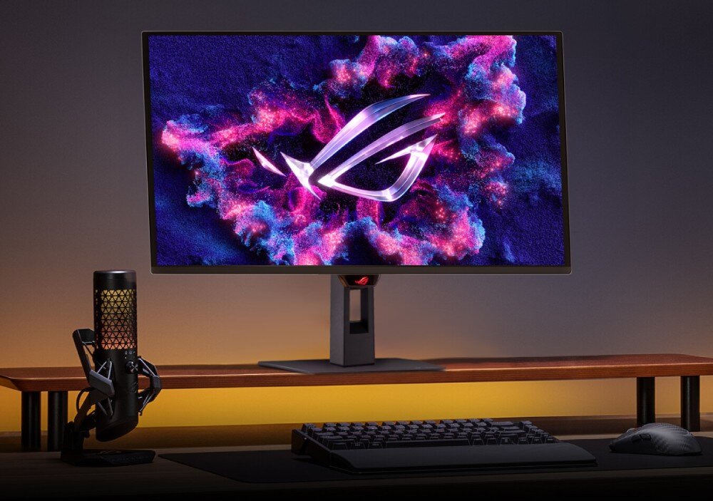 Monitor ASUS ROG Strix XG27AQDNG Monitor stoi na drewnianej podstawce na biurku, po lewej stronie znajduje się mikrofon z podświetleniem, a przed ekranem leży czarna klawiatura oraz myszka komputerowa, przekątna, rozdzielczość, powłoka matrycy