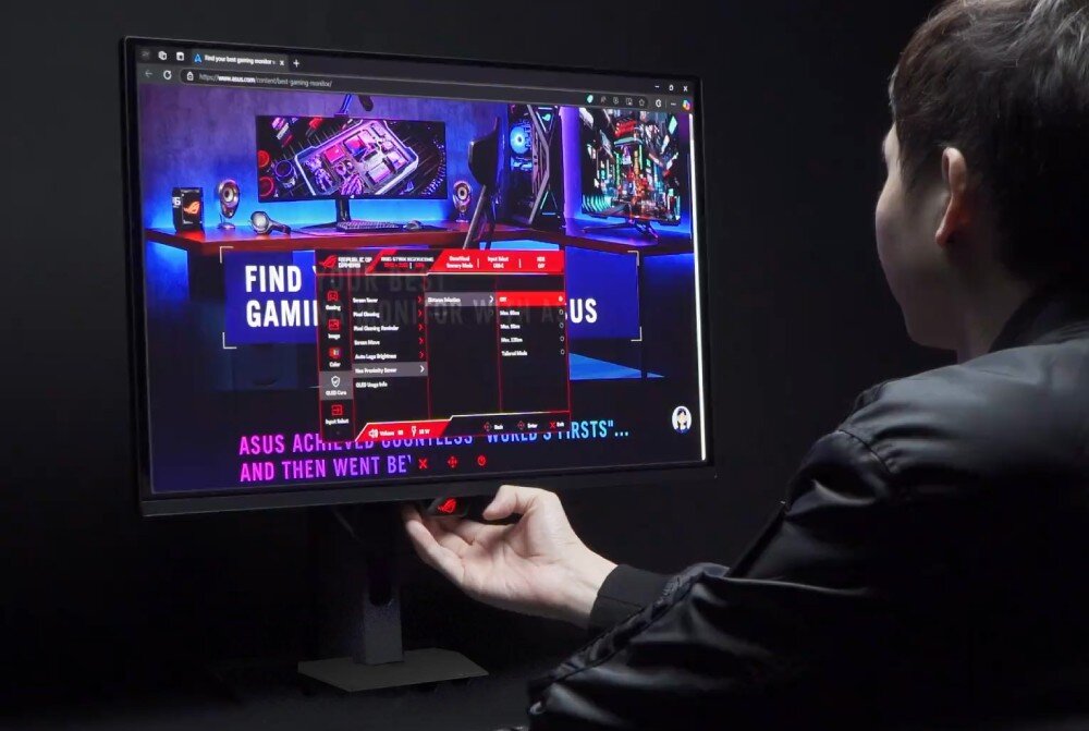 Monitor ASUS ROG Strix XG27AQDNG Mężczyzna siedzi tyłem i patrzy na ekran monitora, na którym wyświetla się strona internetowa z otwartym czerwonym menu ustawień systemowych, podtrzymując dłonią dolną krawędź obudowy, ochrona matrycy, funkcje