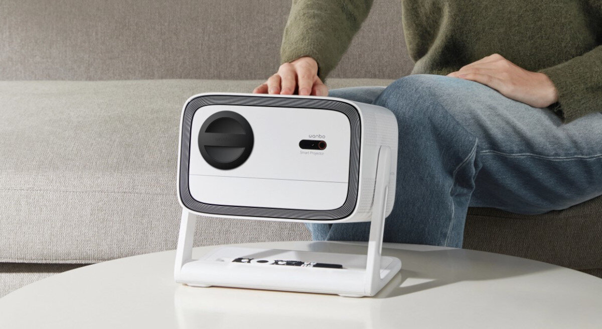 WANBO Vali 1 projektor Full HD 1920x1080 pikseli wyraźny obraz, osoba siedząca na kanapie, projektor stojący na stoliku