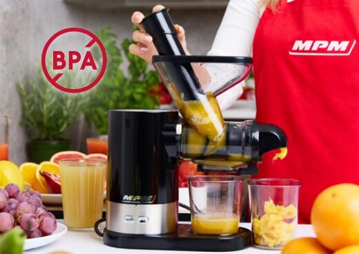 Wyciskarka wolnoobrotowa MSO-17 w trakcie pracy. Osoba w czerwonym fartuchu dotyka urządzenia. Sok spływa do szklanki.