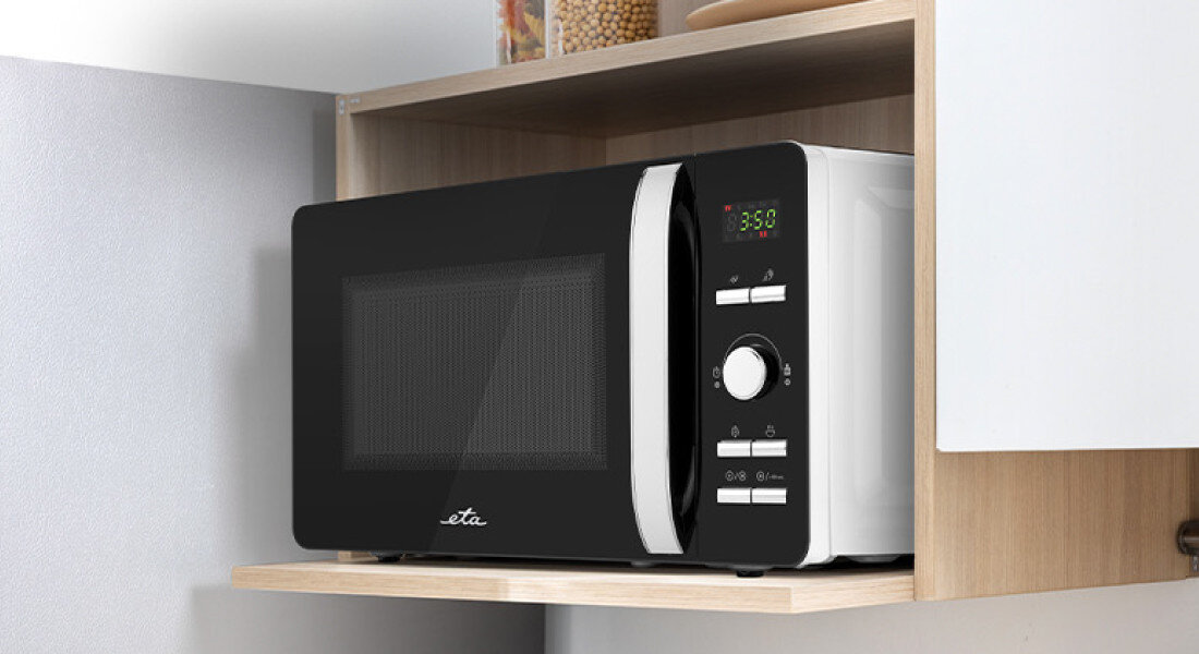 Kuchenka mikrofalowa ETA Gavento ETA120990000 Drugie zdjęcie ukazuje tę samą kuchenkę mikrofalową ustawioną na jasnej, drewnianej półce w kuchennej zabudowie. Front urządzenia jest identycznie wyeksponowany jak na poprzednim zdjęciu, a otoczenie tworzą jasne ściany i szafki oraz pojemniki z produktami spożywczymi szybkie podgrzewanie oszczędność czasu wygodne gotowanie równomierne grzanie 700 W szybkie dania