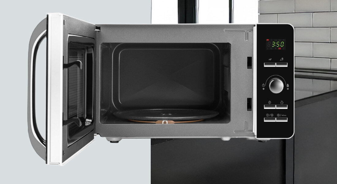 Kuchenka mikrofalowa ETA Gavento ETA120990000 Zdjęcie ukazuje mikrofalówkę sfotografowaną od przodu z otwartymi drzwiczkami, z dobrze widoczną metalową komorą oraz szklanym talerzem obrotowym w środku. Po prawej stronie znajduje się panel sterowania z wyświetlaczem, pokrętłem i przyciskami, a tło tworzy fragment kuchni z czarnym blatem i białymi płytkami kompaktowy rozmiar 20 litrów talerz obrotowy design oszczędność miejsca stylowa kuchnia