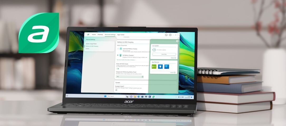 Na obrazie widoczny jest laptop marki Acer z otwartym ekranem, na którym wyświetlany jest interfejs systemu Windows. Obok laptopa znajduje się stos książek, a w tle widoczne jest rozmyte wnętrze pomieszczenia.
