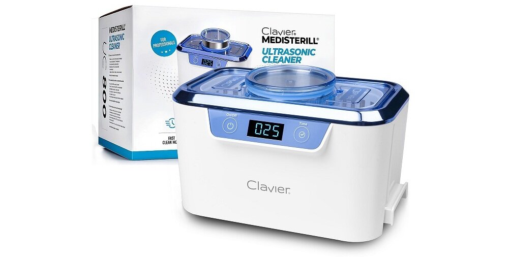 Na zdjęciu znajduje się biała myjka ultradźwiękowa z niebieskim wyświetlaczem pokazującym \'025\'. W tle widoczne jest opakowanie z napisem \'Clavier MEDISTERILL ULTRASONIC CLEANER\'.