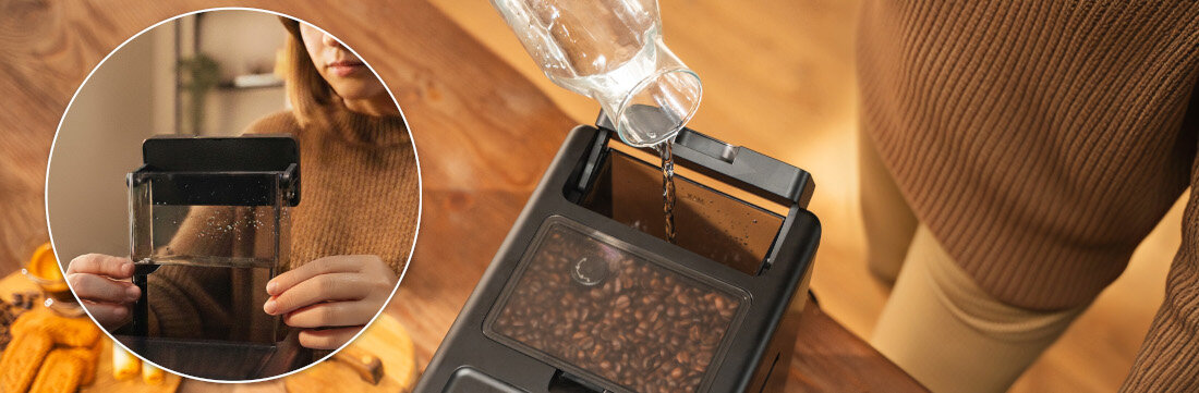 Osoba nalewa wodę z dzbanka do ekspresu do kawy, w którym widać ziarna kawy. W okrągłym zbliżeniu pokazano osobę trzymającą pojemnik na wodę.