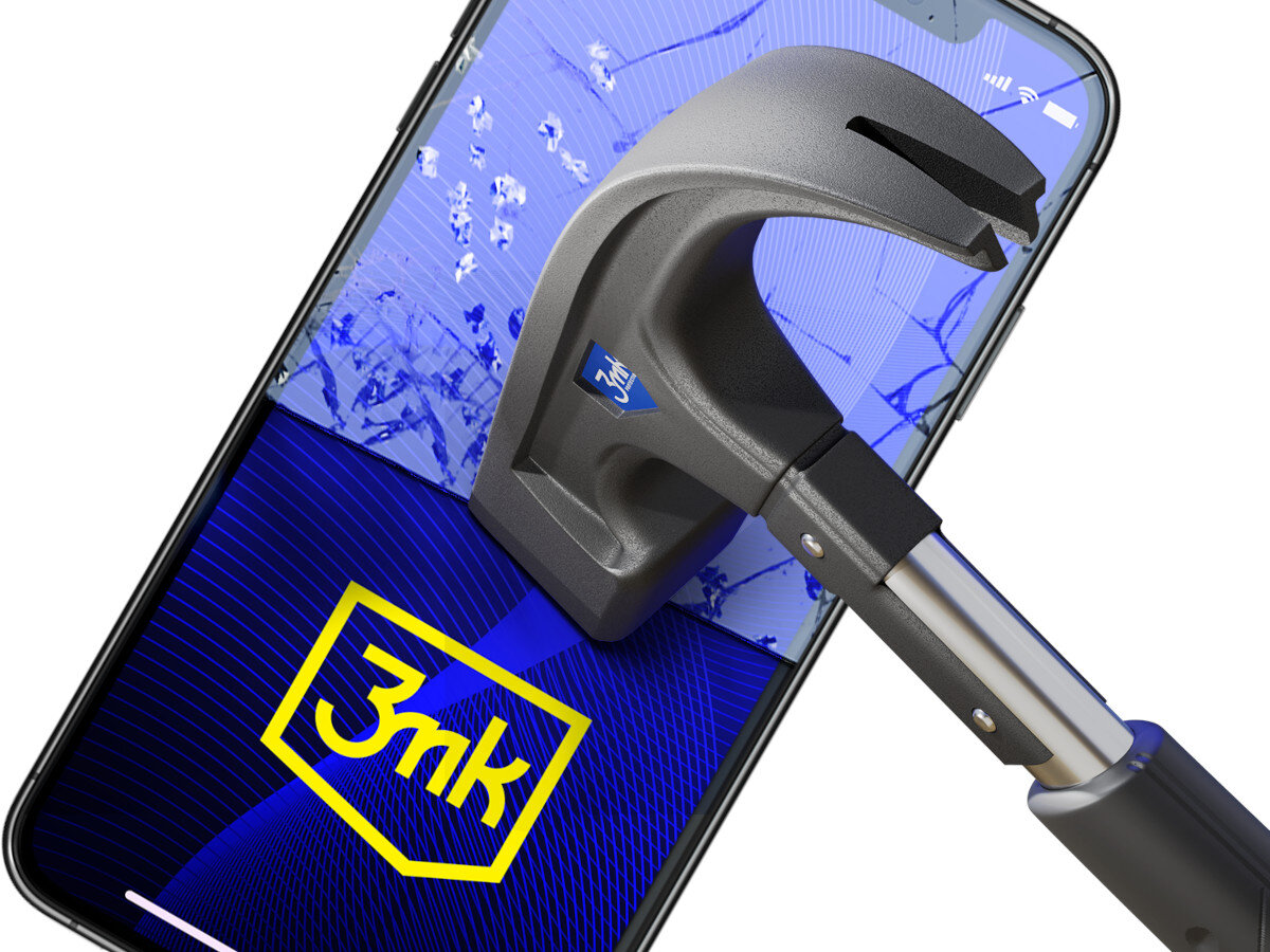 Na obrazie widoczny jest smartfon z pękniętym ekranem, na którym znajduje się logo \'3mk\' w żółtej ramce. Na ekranie opiera się metalowy młotek, sugerujący test wytrzymałości szkła ochronnego.
