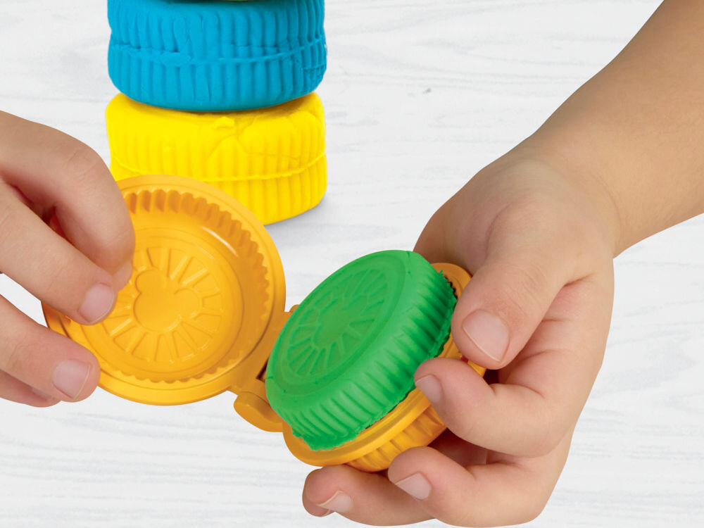 Ciastolina PLAY-DOH Disney Junior Mickey Mouse Przenośny garaż Dłonie dziecka używające żółtej, okrągłej foremki Play-Doh do formowania ciastoliny. Wewnątrz foremki widoczny wytłoczony wzór głowy Myszki Miki, a obok gotowe, zielone i niebieskie krążki z masy plastycznej.