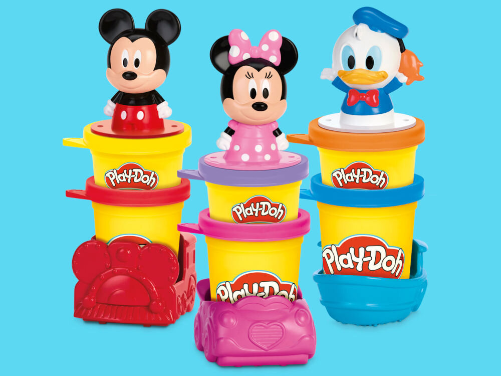 Ciastolina PLAY-DOH Disney Junior zestaw pieczątek G31105L0 Dziecko odciska wzory w czerwonej walizeczce Play-Doh Mickey Mouse. Na matrycy widoczne kolorowe kształty z masy plastycznej: niebieska głowa Myszki Miki z teksturą, żółte serce, zielona dłoń oraz żółte koło zębate.