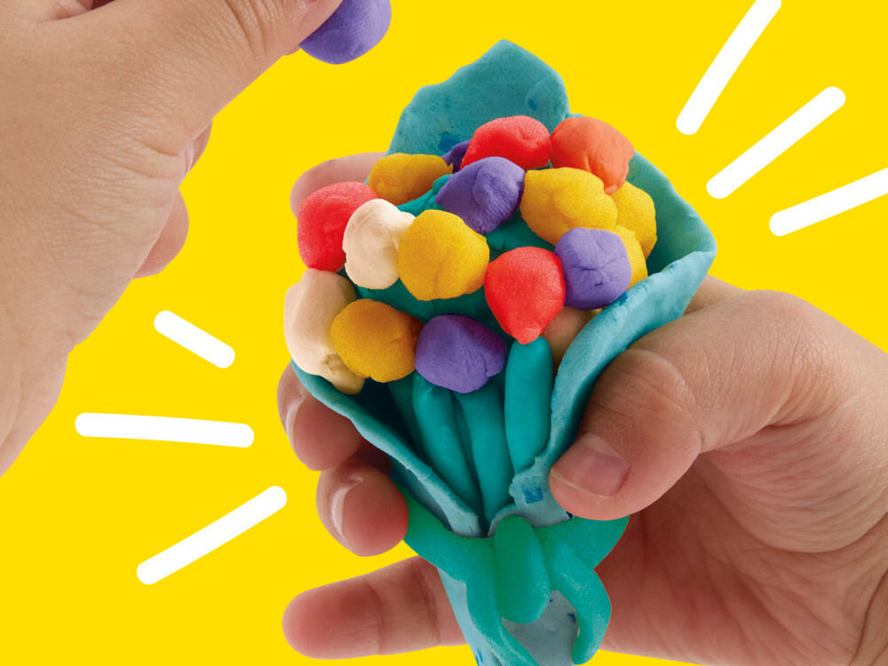 Ciastolina PLAY-DOH Twórz i świętuj zestaw 20 tub G24675L0 Dłonie dziecka używające turkusowej, dwuczęściowej foremki Play-Doh do formowania babeczki z różowej ciastoliny. Babeczka posiada dekoracyjny wierzch w kształcie głowy Myszki Minnie z charakterystyczną kokardą.