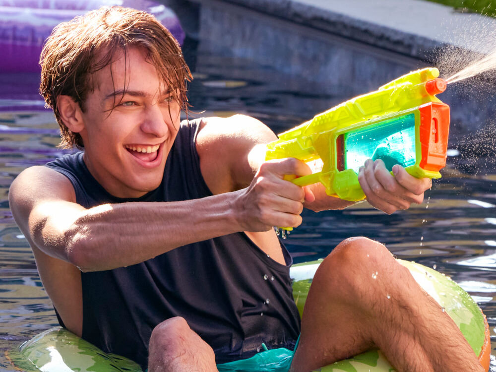 Wyrzutnia NERF Super Soaker Dunk-Fill+ G21465L0 Uśmiechnięty chłopak w basenie strzelający wodą z limonkowej wyrzutni Nerf Super Soaker Dunk Fill.