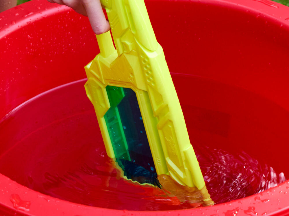 Wyrzutnia NERF Super Soaker Dunk-Fill+ G21465L0 Ręka zanurzająca wyrzutnię Nerf Super Soaker Dunk Fill w czerwonym wiadrze z wodą w celu szybkiego napełnienia zbiornika.