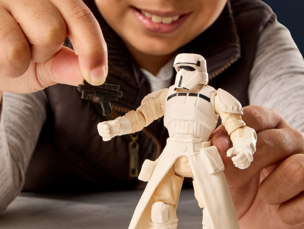 Figurka HASBRO Star Wars ActionVerse AT-RT Vehicle G28405L0 Zbliżenie na dłoń dziecka wkładającą mały czarny blaster w rękę figurki Imperial Drivera. Detal pokazuje precyzyjne wykonanie akcesoriów i ruchome dłonie figurki Star Wars.