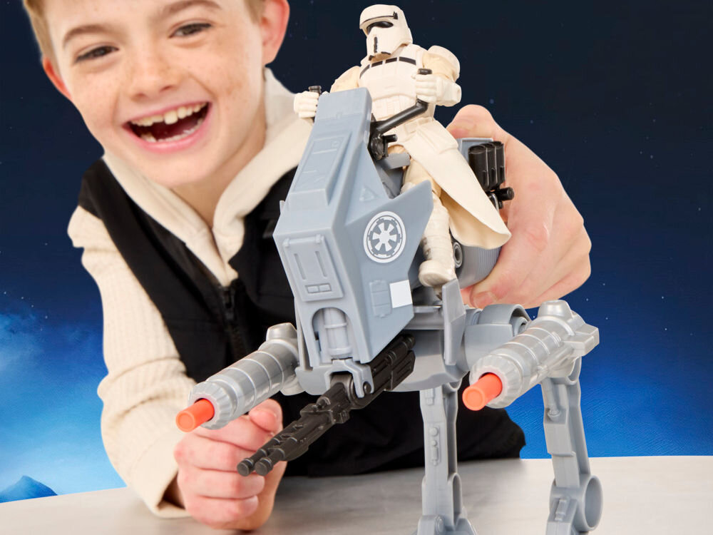 Figurka HASBRO Star Wars ActionVerse AT-RT Vehicle G28405L0 Uśmiechnięty chłopiec podczas zabawy zestawem Star Wars Mission Fleet. Widok z przodu na maszynę AT-RT z zamontowanymi działkami i siedzącym na górze szturmowcem w białym pancerzu.