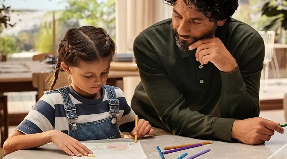 Dziecko z ojcem patrzące na zeszyt
