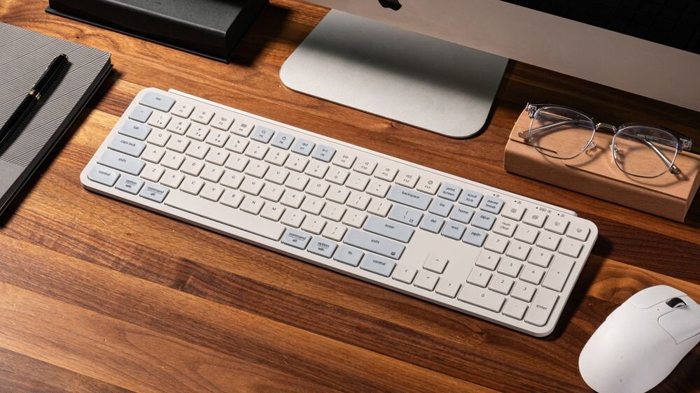 Keychron B6 Pro - Klawiatura ułożona na dwukolorowej podkładce na biurku, obok myszy komputerowej oraz okularów.