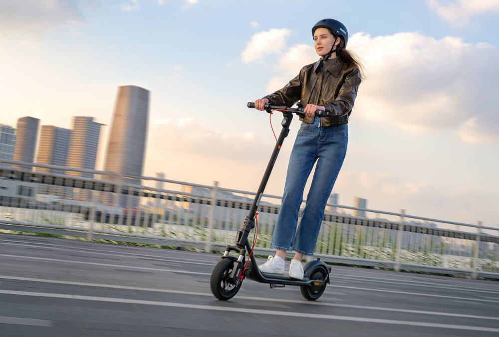 Hulajnoga elektryczna SEGWAY F2 Pro D II 65km 900W 10 cali Czarny miasto osoba jedzie pod górkę na hulajnodze po drodze w tle niebo budynki silnik o mocy 900 W cicha praca i płynna kontrola prędkości pokonywanie wzniesień o nachyleniu do 22% maksymalna prędkość do 20 km/h