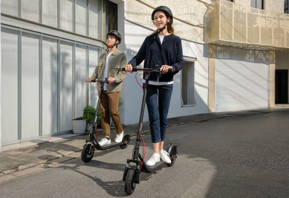 Hulajnoga elektryczna SEGWAY F2 Pro D II 65km 900W 10 cali Czarny miasto budynki dwie osoby jadą na hulajnogach obok siebie 3 tryby jazdy tryb ECO prędkość do 6 km/h tryb DRIVE prędkość do 15 km/h tryb SPORT prędkość do 20 km/h