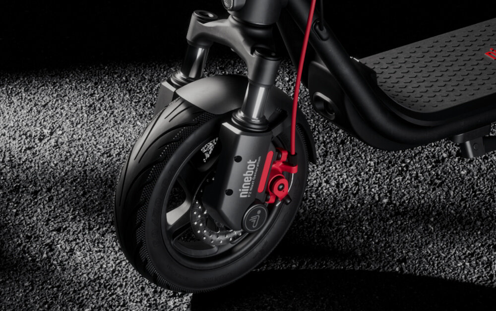 Hulajnoga elektryczna SEGWAY F2 Pro D II 65km 900W 10 cali Czarny droga zbliżenie na przenie koło widok na amortyzator przednie podwójne zawieszenie sprężynowe ze skokiem 30 mm profesjonalny system zawieszenia skutecznie tłumi wstrząsy sprzyja wygodnemu podróżowaniu