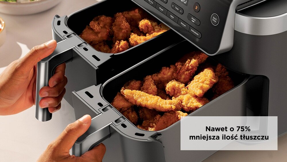 Osoba trzyma frytkownicę beztłuszczową z podwójnym koszem, wypełnioną smażonym jedzeniem. Na obrazie widoczny jest tekst: \'Nawet o 75% mniejsza ilość tłuszczu\'.