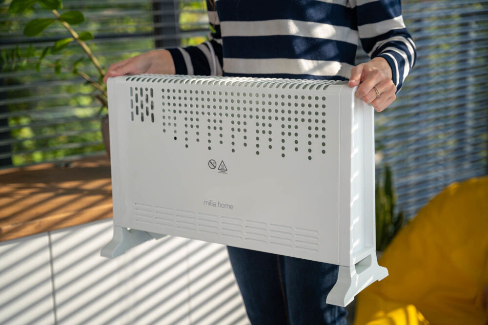 Grzejnik konwektorowy MILLA HOME MCH104 grzejnik przenoszony przez kogoś trzymany za uchwyty
