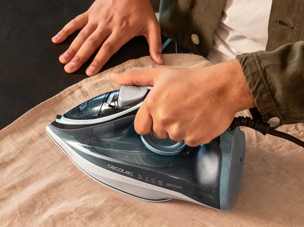 Osoba prasuje tkaninę za pomocą żelazka marki Cecotec o mocy 2600W. Na żelazku widoczne jest logo \'cecotec\' oraz oznaczenie \'2600W\'.