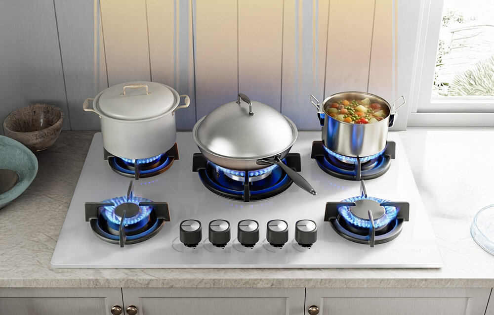 Płyta gazowa ISEASY MGBG-775 Trzy garnki ustawione na różnych palnikach pokazują możliwość przygotowania kilku dań równocześnie. Niebieskie płomienie równomiernie ogrzewają naczynia, co ułatwia gotowanie wielu potraw naraz