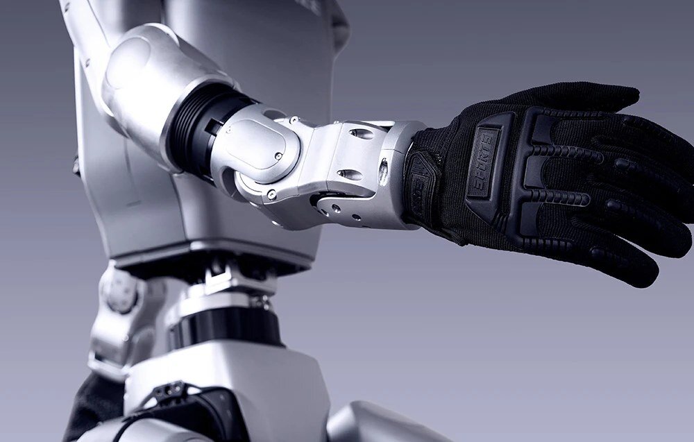 Sekcja o możliwościach edukacyjno-badawczych: Mechaniczne ramię robota humanoidalnego z pięciopalczastą dłonią ubraną w czarną rękawicę.
