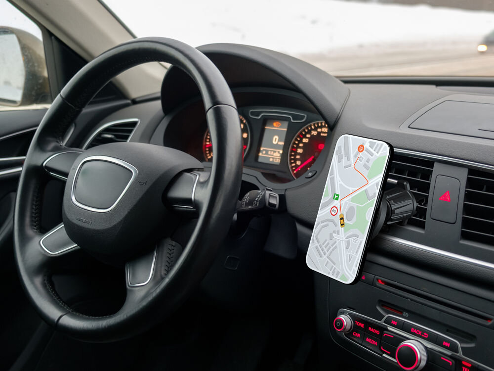 WANDOO WCH400 magnetyczny uchwyt samochodowy MagSafe na kratkę nawiewu z magnesem N52 Zdjęcie wnętrza samochodu Audi A3 z kierownicą, deską rozdzielczą i przymocowanym do kratki nawiewu uchwytem samochodowym na telefon. Na telefonie wyświetlana jest mapa nawigacyjna.