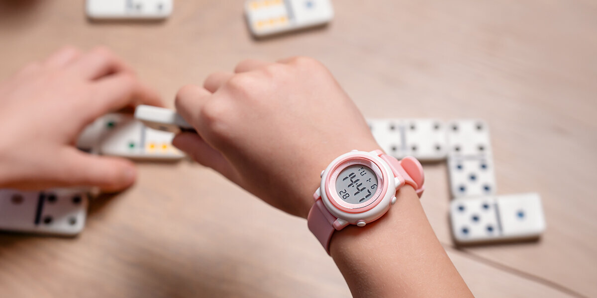 Smartwatch SPONGE WatchMe Kids na dłoni dziecka układającego domino.