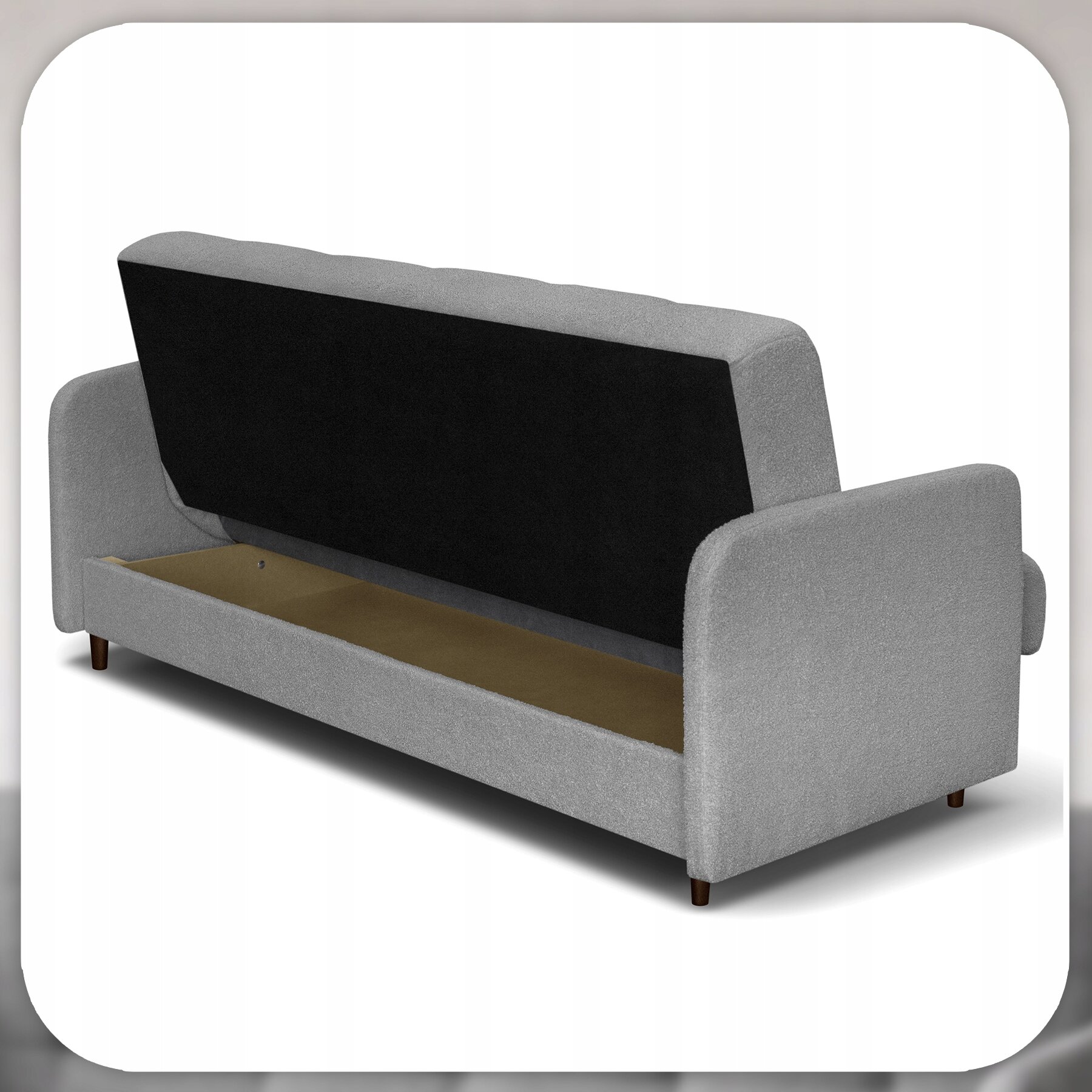 Szara sofa z funkcją spania, z otwartym schowkiem na pościel pod siedziskiem. Sofa ma zaokrąglone podłokietniki i stoi na drewnianych nóżkach.