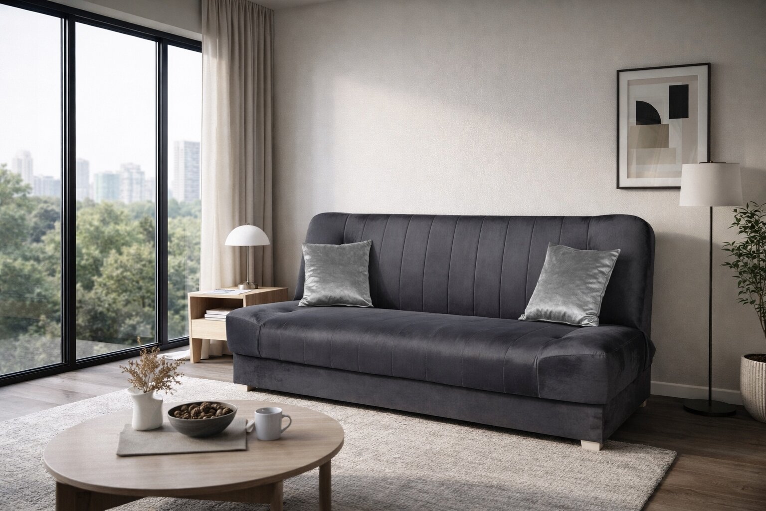 Szara welurowa sofa z funkcją spania stoi w nowoczesnym salonie z dużym oknem. Obok sofy znajduje się stolik z lampką i dekoracyjnymi poduszkami.