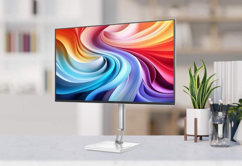 Monitor ACER CE270UXwmiipprx Monitor komputerowy z kolorową grafiką na ekranie stoi na białym biurku w jasnym biurze obok rośliny w doniczce oraz przyborów piśmienniczych, opis