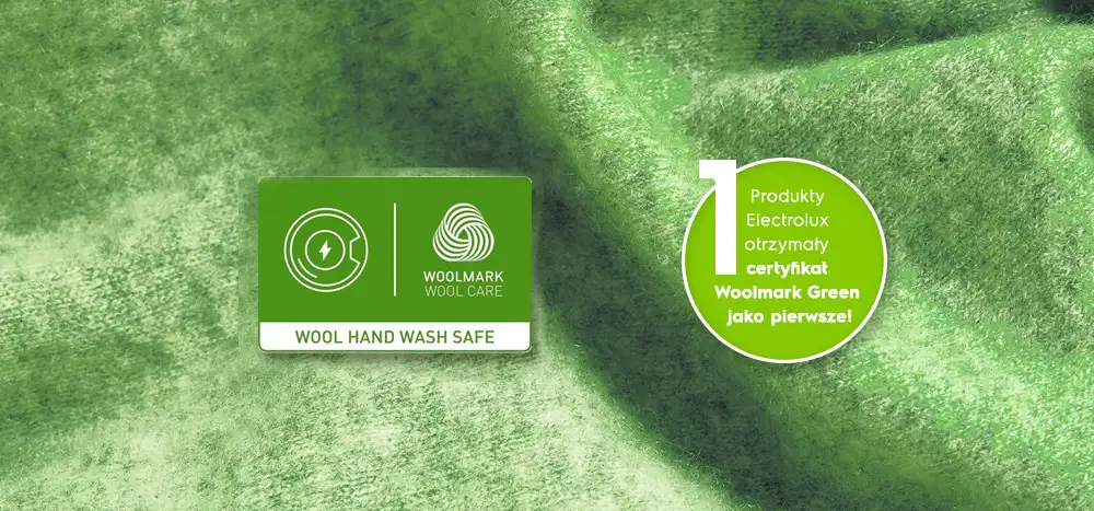Obraz przedstawia zielone tło z dwoma elementami graficznymi. Po lewej stronie znajduje się logo \'WOOL HAND WASH SAFE\' i \'WOOLMARK WOOL CARE\', a po prawej okrągły znak z tekstem: \'Produkty Electrolux otrzymały certyfikat Woolmark Green jako pierwsze!\'.