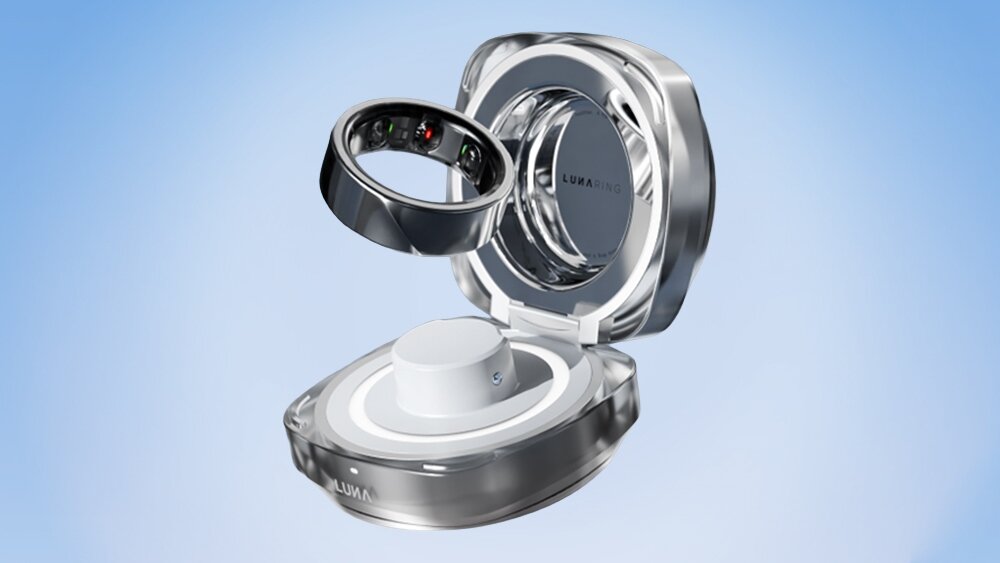 Na obrazie widoczny jest czarny pierścień z wnętrzem zawierającym czujniki, umieszczony nad otwartym etui. Na etui widnieje napis \'LUNA RING\'.
