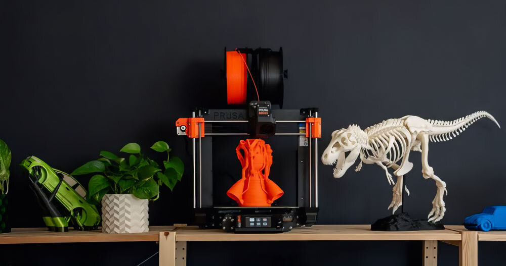 Drukarka 3D PRUSA MK4S Wi-Fi, LAN (Zmontowana) drukarka na półce ciemna ściana obok wydrukowane rzeczy praca offline, prywatność danych, bezpieczeństwo projektów