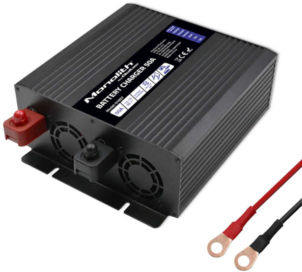 Na obrazie widoczna jest czarna ładowarka z napisem \'Monolith BATTERY CHARGER 50A\' oraz dwoma wentylatorami. Obok znajdują się dwa przewody z końcówkami w kolorze czerwonym i czarnym.