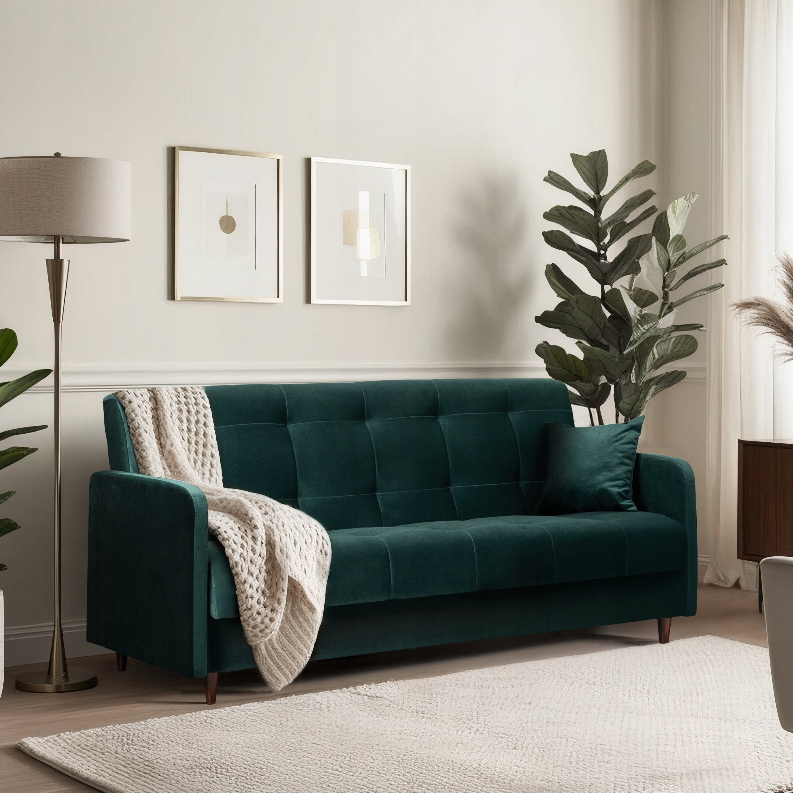 Zielona welurowa sofa z funkcją spania stoi w elegancko urządzonym salonie, obok niej znajduje się lampa podłogowa i roślina doniczkowa. Na ścianie wiszą dwa minimalistyczne obrazy, a na sofie leży jasny koc.