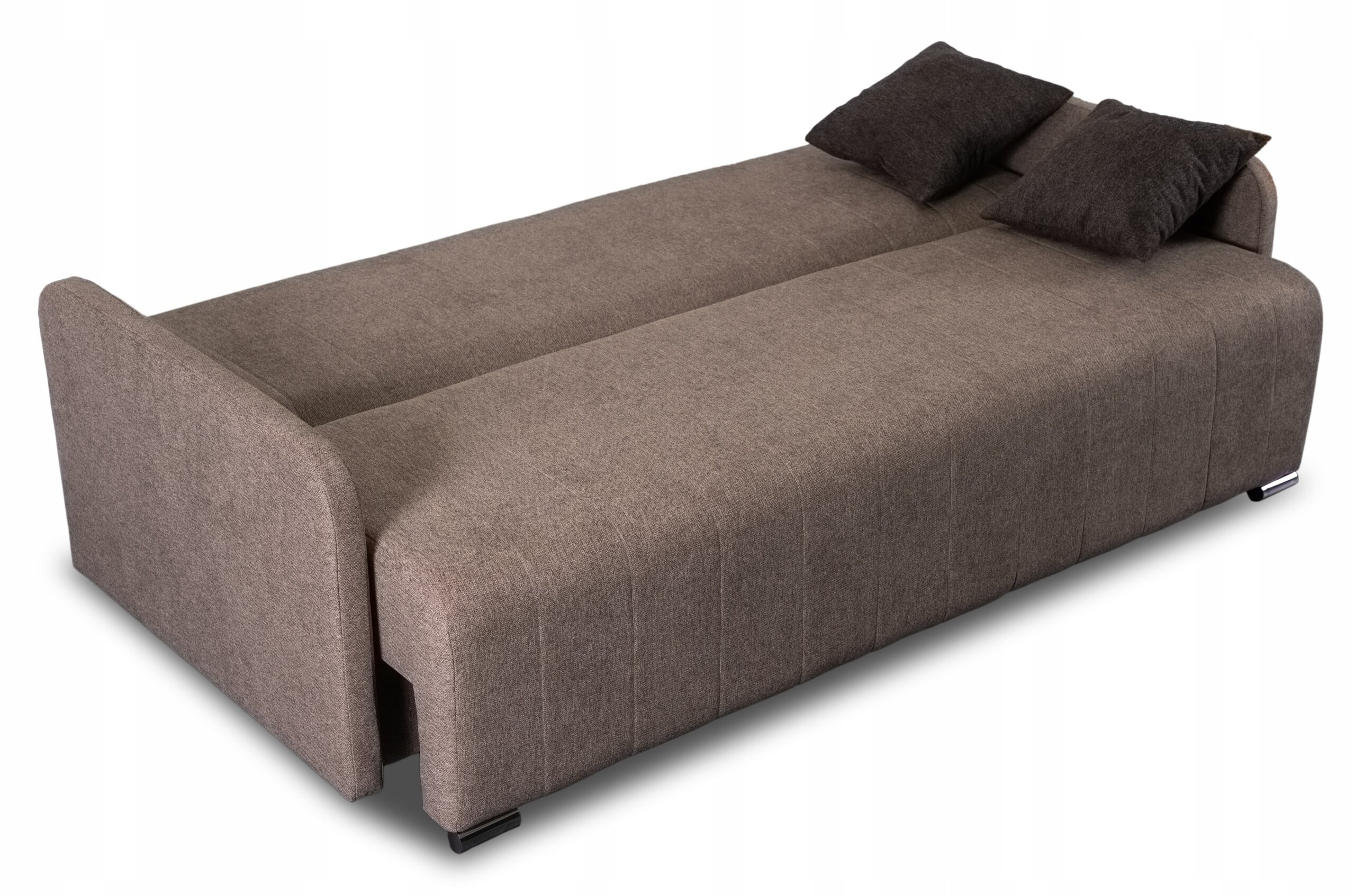 Na obrazie widoczna jest rozłożona sofa w kolorze beżowym z dwoma ciemnymi poduszkami. Sofa ma prosty, nowoczesny design i funkcję spania.