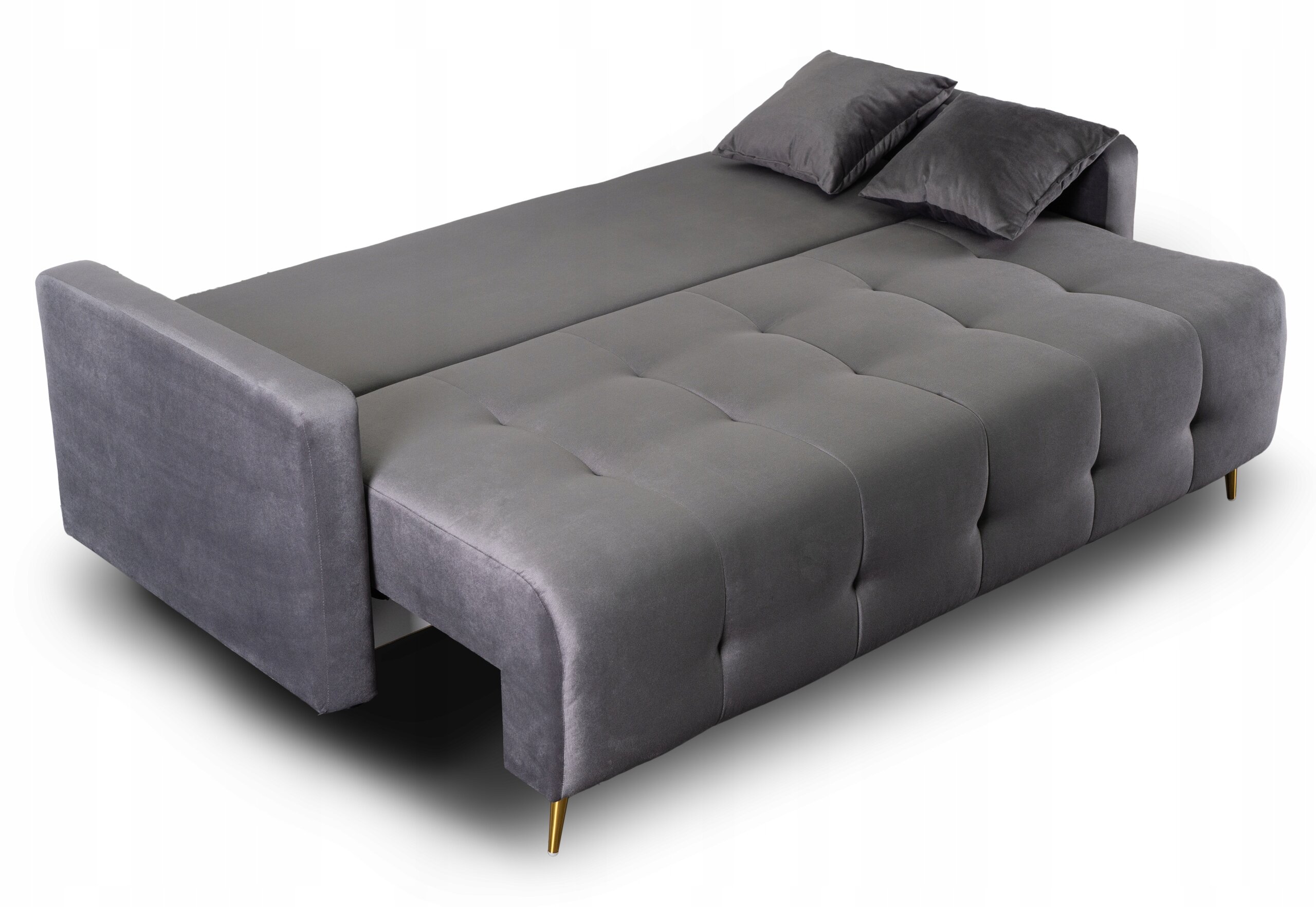 Szara, rozkładana sofa z funkcją spania, z dwoma poduszkami i złotymi nóżkami. Powierzchnia sofy jest pikowana, a materiał wygląda na miękki.