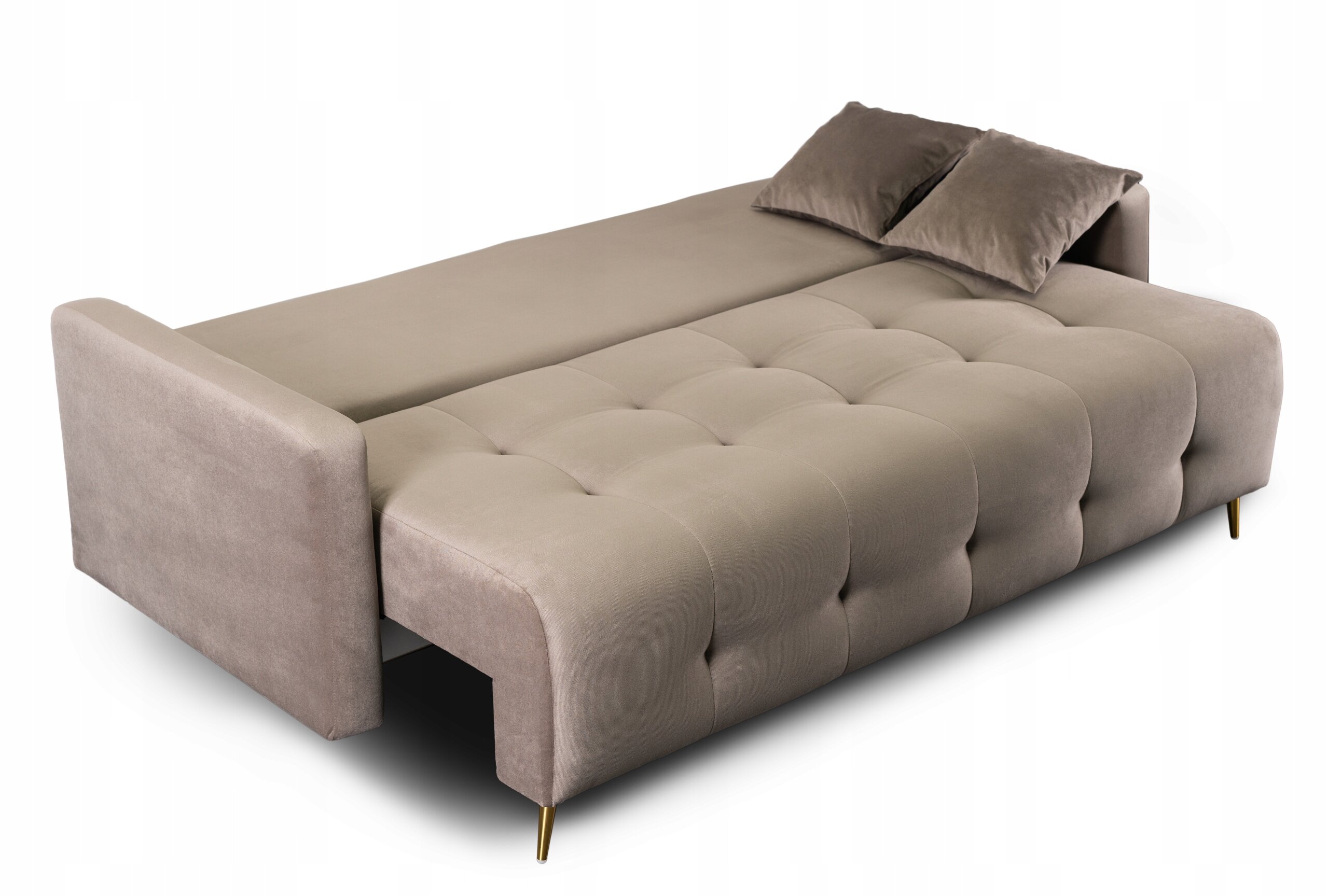 Beżowa, rozkładana sofa z funkcją spania, z dwoma poduszkami i złotymi nóżkami. Powierzchnia siedziska jest pikowana.