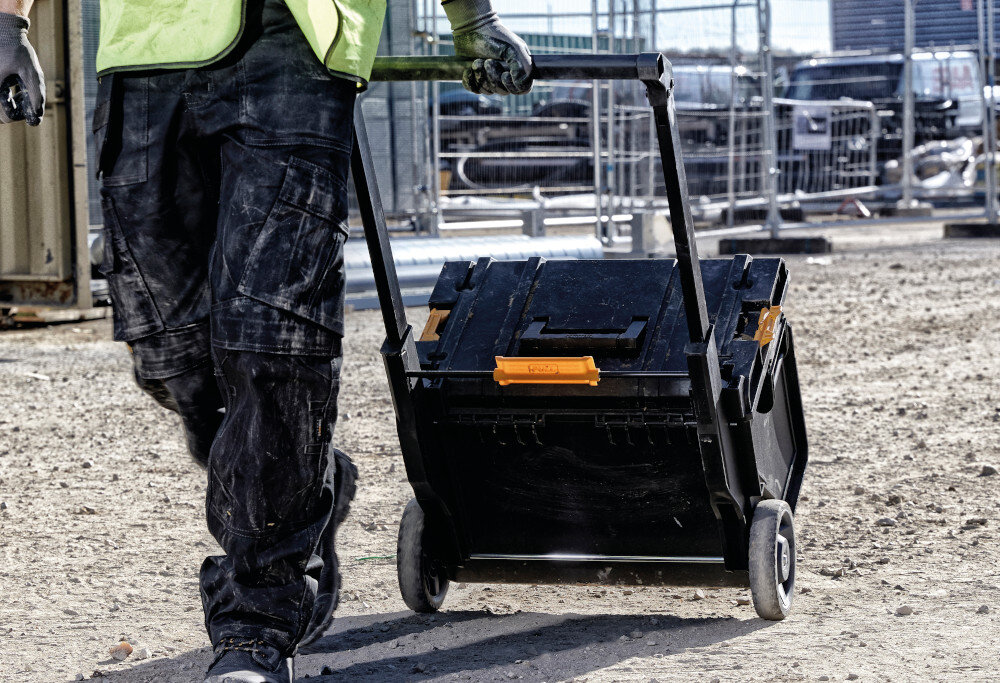 Skrzynka narzędziowa DEWALT DS450 plac budowy osoba ciągnie za sobą skrzynię praktyczny gadżet pomaga uporządkować narzędzia akcesoria i drobne elementy montażowe efektywność codziennej pracy wymiary 554 × 685 × 500 mm