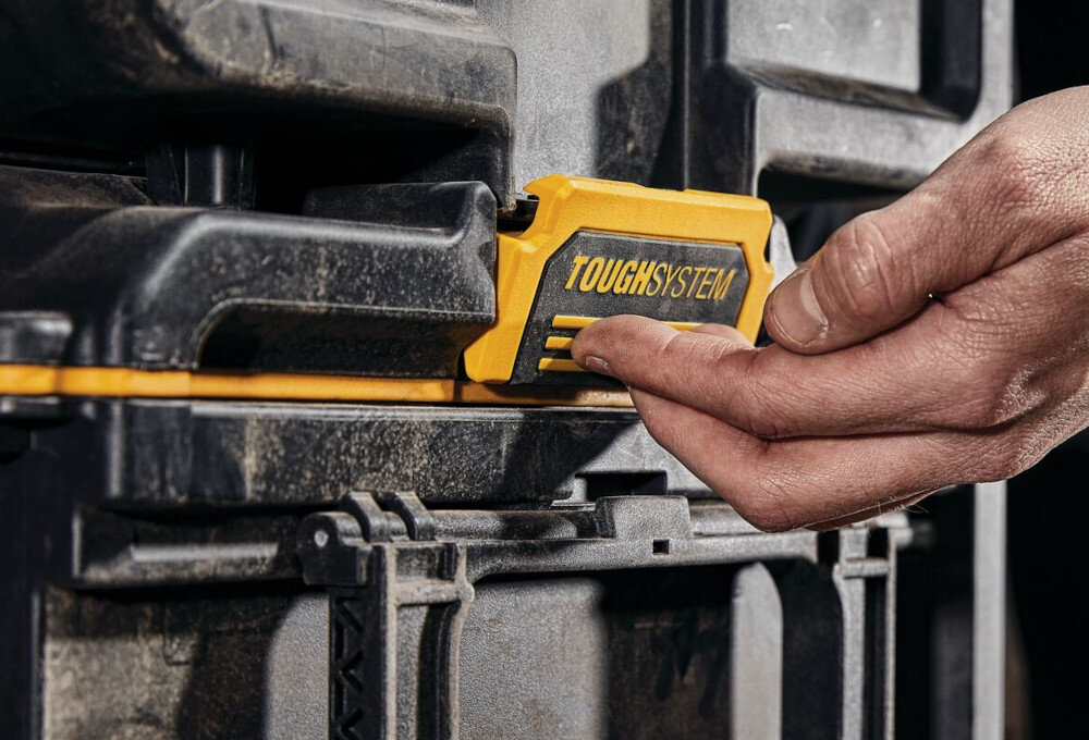 Skrzynka narzędziowa DEWALT DS450 zbliżenie na uchwyt d montażu w systemie ToughSystem osoba trzyma uchwyt w dłoni należy do systemu ToughSystem 2.0 Toolbox w pełni kompatybilna z produktami ToughSystem pierwszej generacji można łączyć nowe elementy z już posiadanymi modułami dowolnie rozbudowywać zestaw