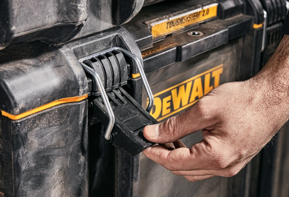 Skrzynka narzędziowa DEWALT DS450 zbliżenie na zamek osoba trzyma zamek w dłoni dwuczęściowe solidne metalowe zamki bezpieczne przechowywanie narzędzi i akcesoriów ochrona przed przypadkowym otwarciem podczas przenoszenia trwałość całej skrzynki